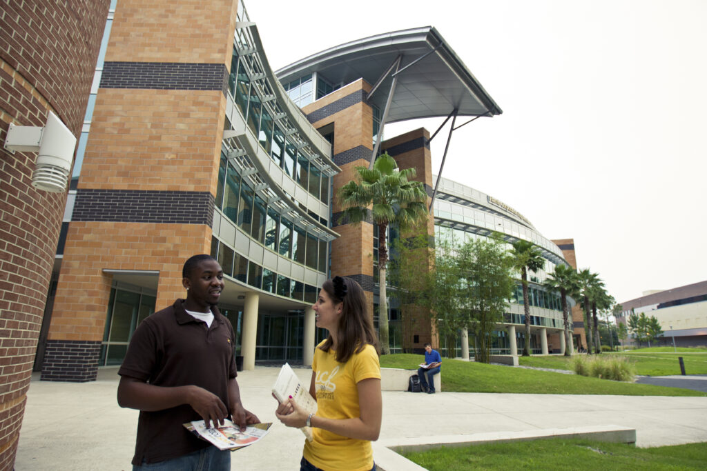 two students talk in front of the L3Harris building