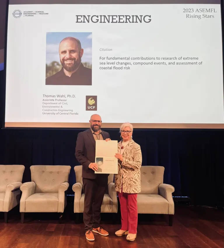 Tom Wahl receives his award in front of screen with his picture